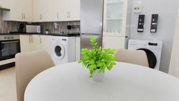 A modern kitchen with white cabinets, a microwave, a washing machine, and a refrigerator.