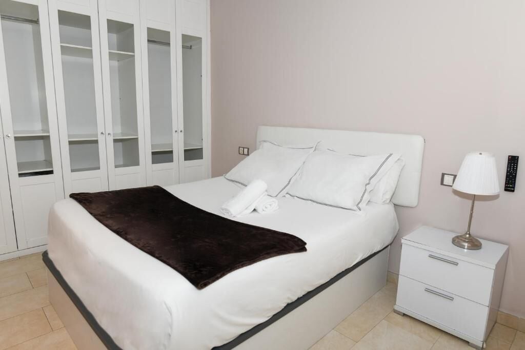 Une chambre à coucher avec un lit, une table de chevet, une lampe et une armoire.
