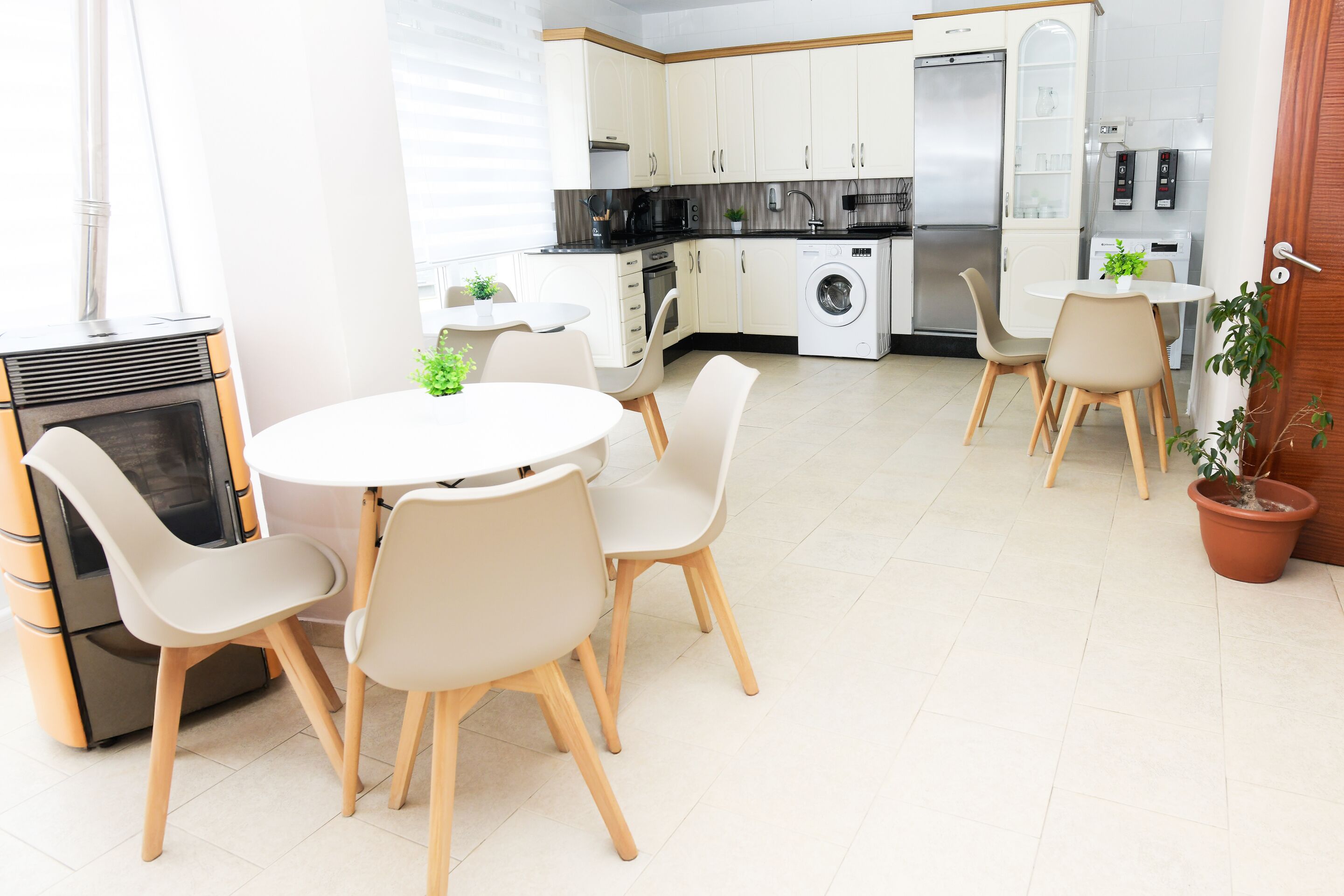 Une cuisine moderne avec des meubles blancs, un lave-linge encastré et un coin repas comprenant une table ronde et des chaises.