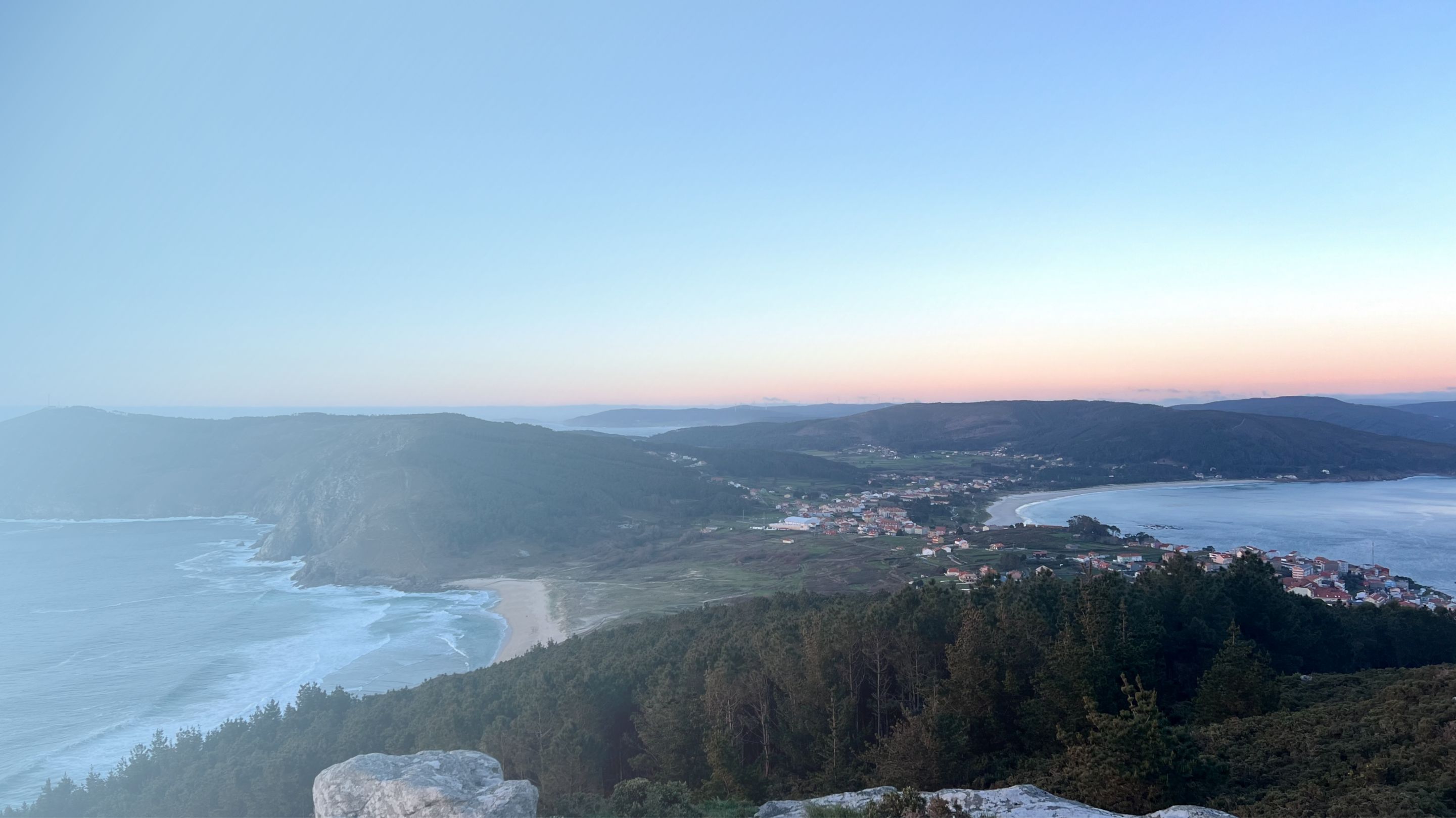 A coastal town with a view of the ocean and hills.