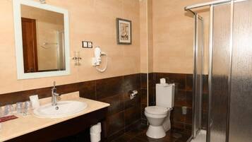 Een badkamer met wastafel, spiegel, toilet en douche.