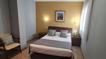 A hotel room with a large bed, two bedside tables, a chair, and a picture on the wall.