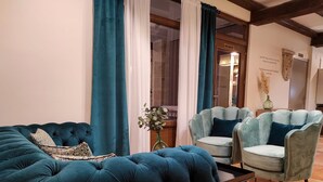 Una sala de estar con un sofá capitonado, dos sillones y una mesita.