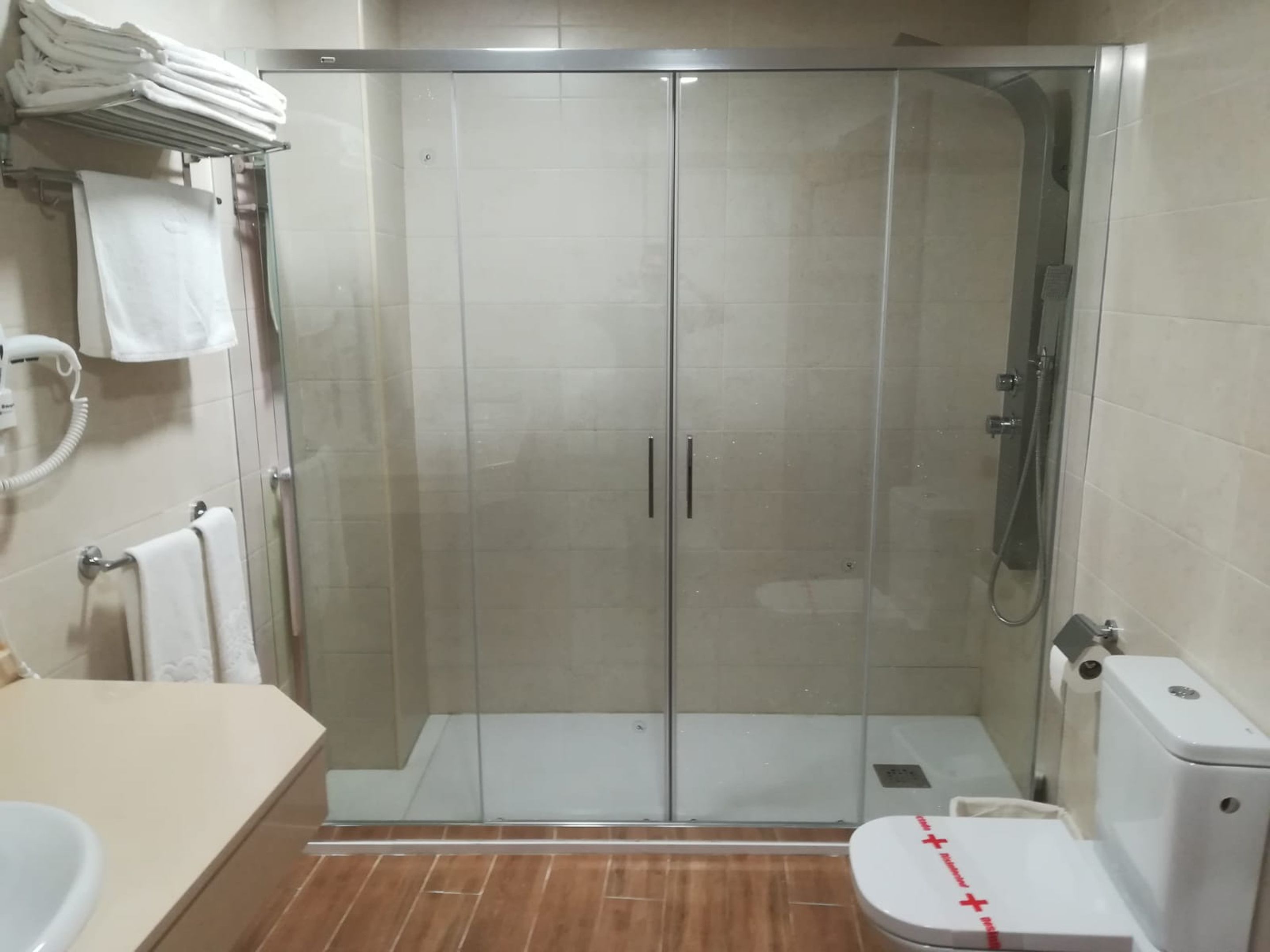 Un baño con ducha de vidrio, inodoro y lavamanos.