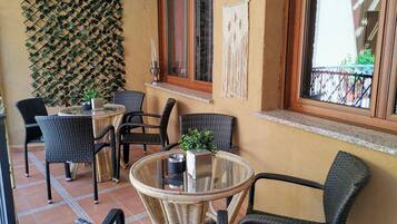 Een terras met rieten meubilair, een glazen tafel en een decoratieve muur met klimplanten.