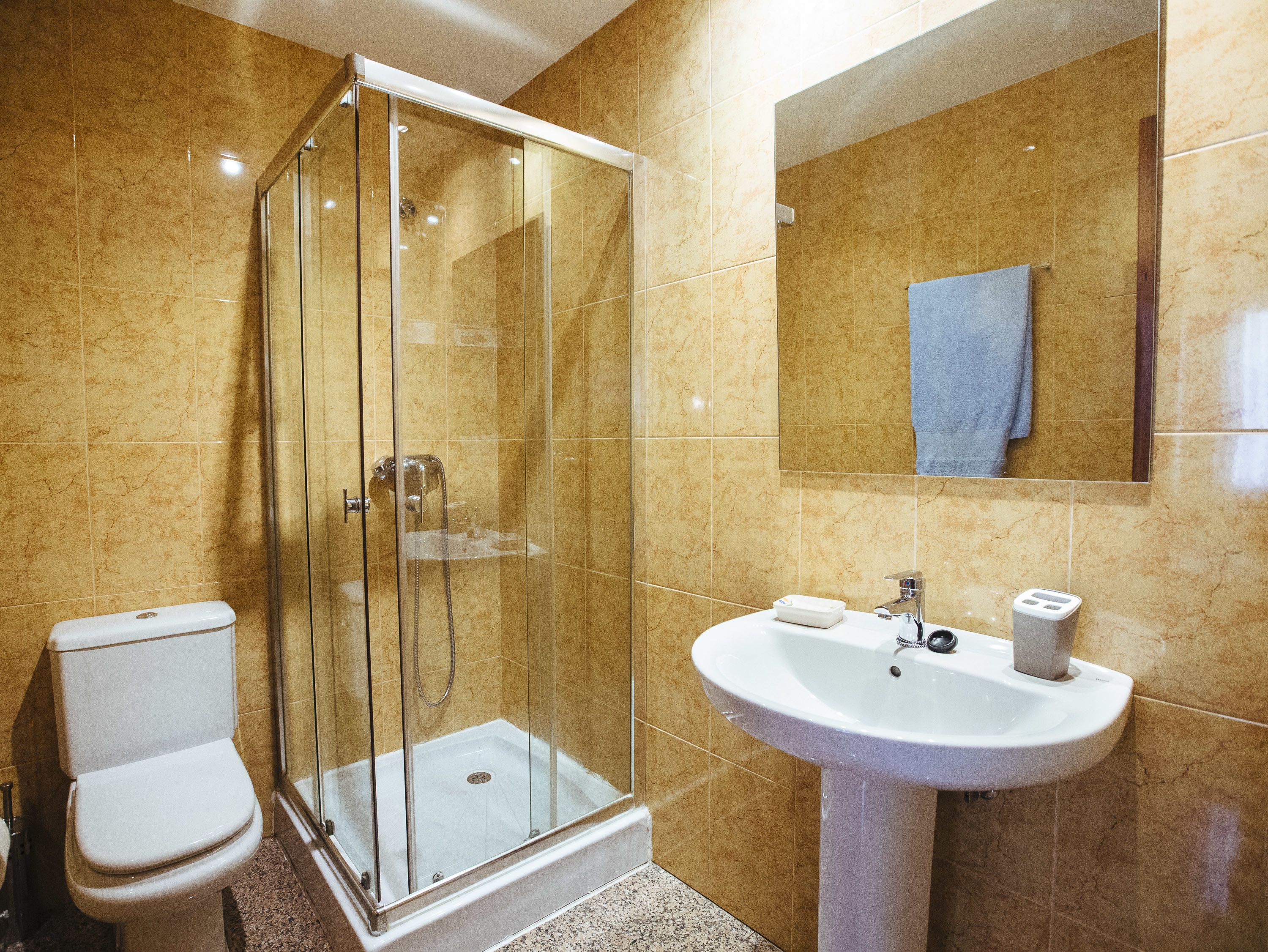 Un baño con ducha envuelta en vidrio, inodoro y lavamanos.