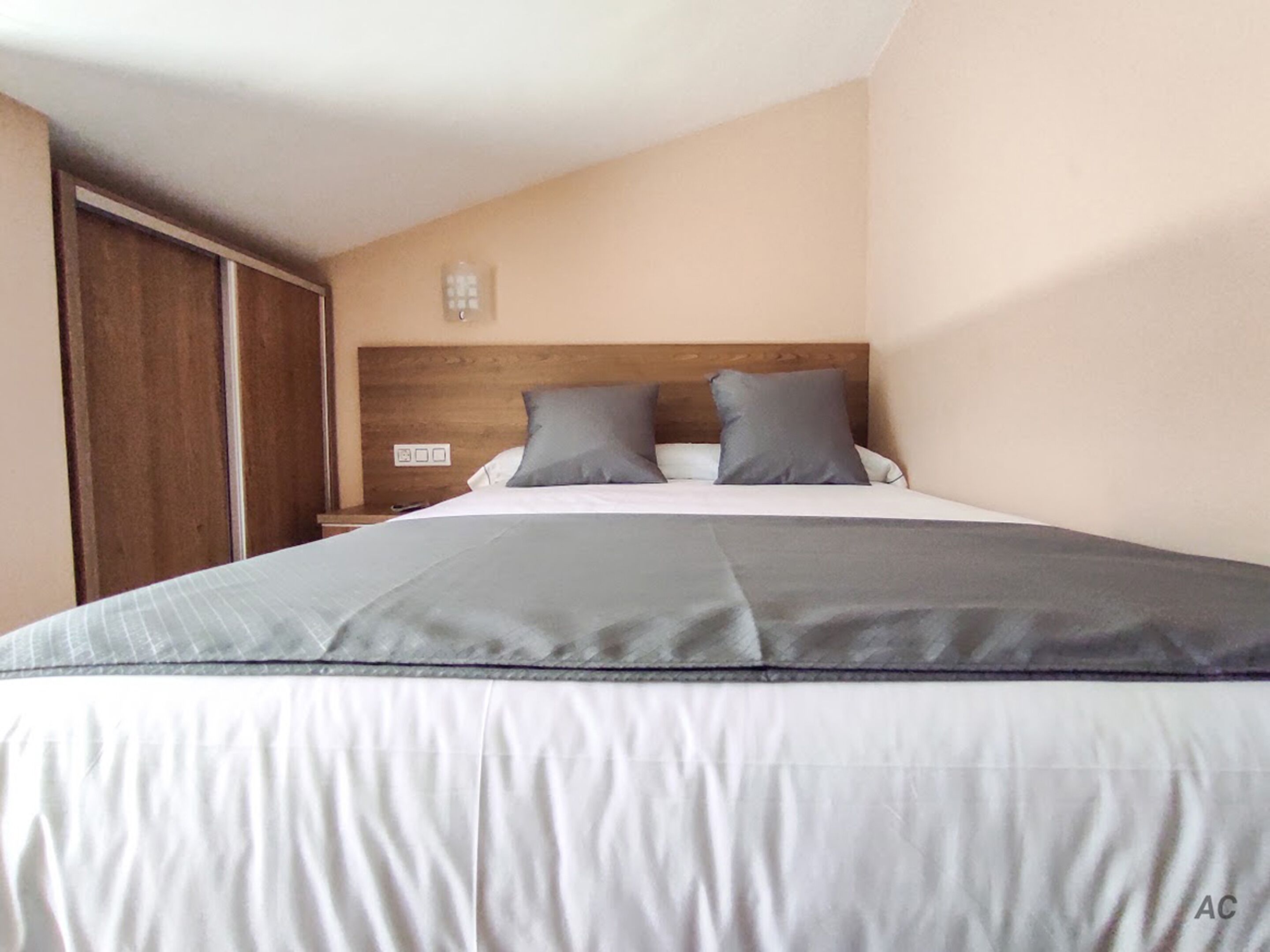 A bedroom with a bed, a wooden headboard, a nightstand, and a wardrobe.