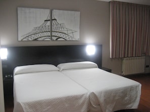 Ein Hotelzimmer mit Bett, einem Kopfteil, einem Fenster mit Vorhängen und einem Bild des Eiffelturms.