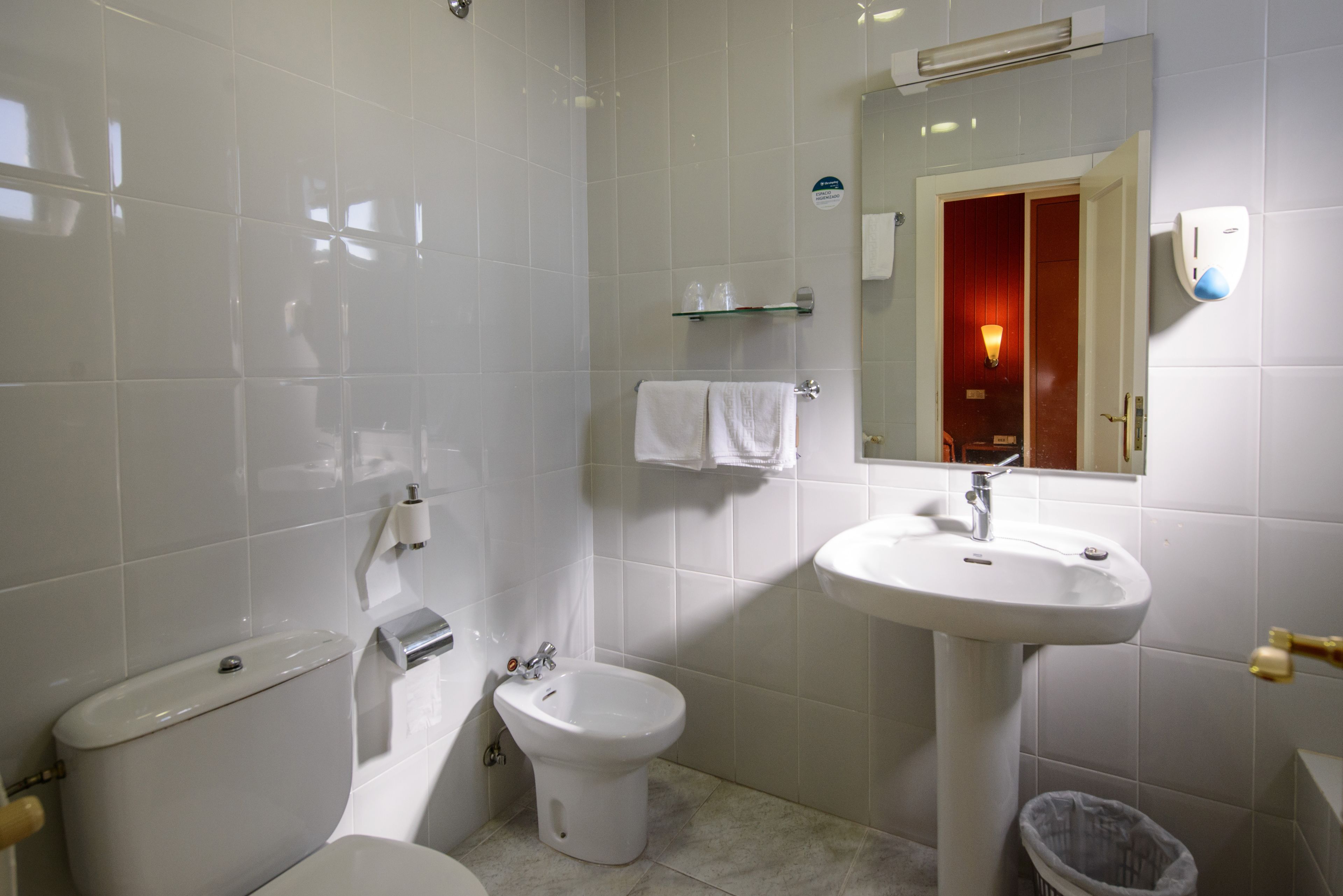 Une salle de bain équipée de toilettes, d’un bidet, d’un lavabo et d’un miroir.