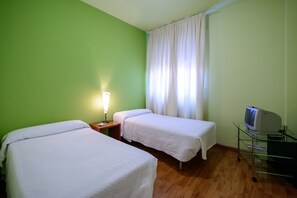 A room with two single beds, a nightstand with a lamp, a TV on a glass stand, and a window with curtains. - El Paso Honroso (Hospital de Orbigo)