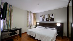 A hotel room with a bed, bedside tables, a desk, and a chair. - El Paso Honroso (Hospital de Orbigo)