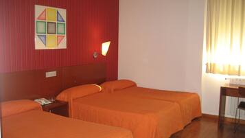 Habitación de hotel con dos camas, aire acondicionado de pared, mesita de noche con lámpara y ventana con cortinas.
