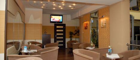 A hotel lobby with seating areas, a television, and a reception desk.