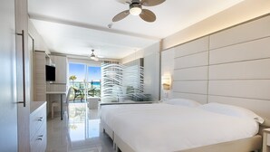 Ein modernes Hotelzimmer mit einem großen Bett, einem Deckenventilator, einem Fernseher und einem Balkon mit Stadtblick.