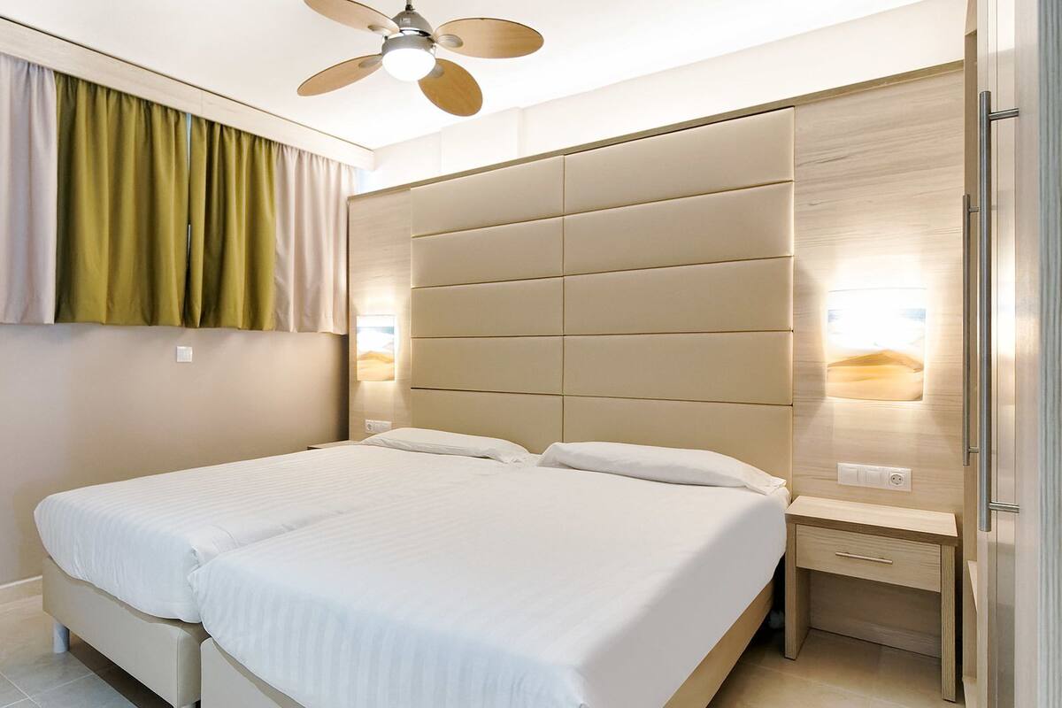 A modern bedroom with a bed, a ceiling fan, a nightstand, and a built-in wardrobe.