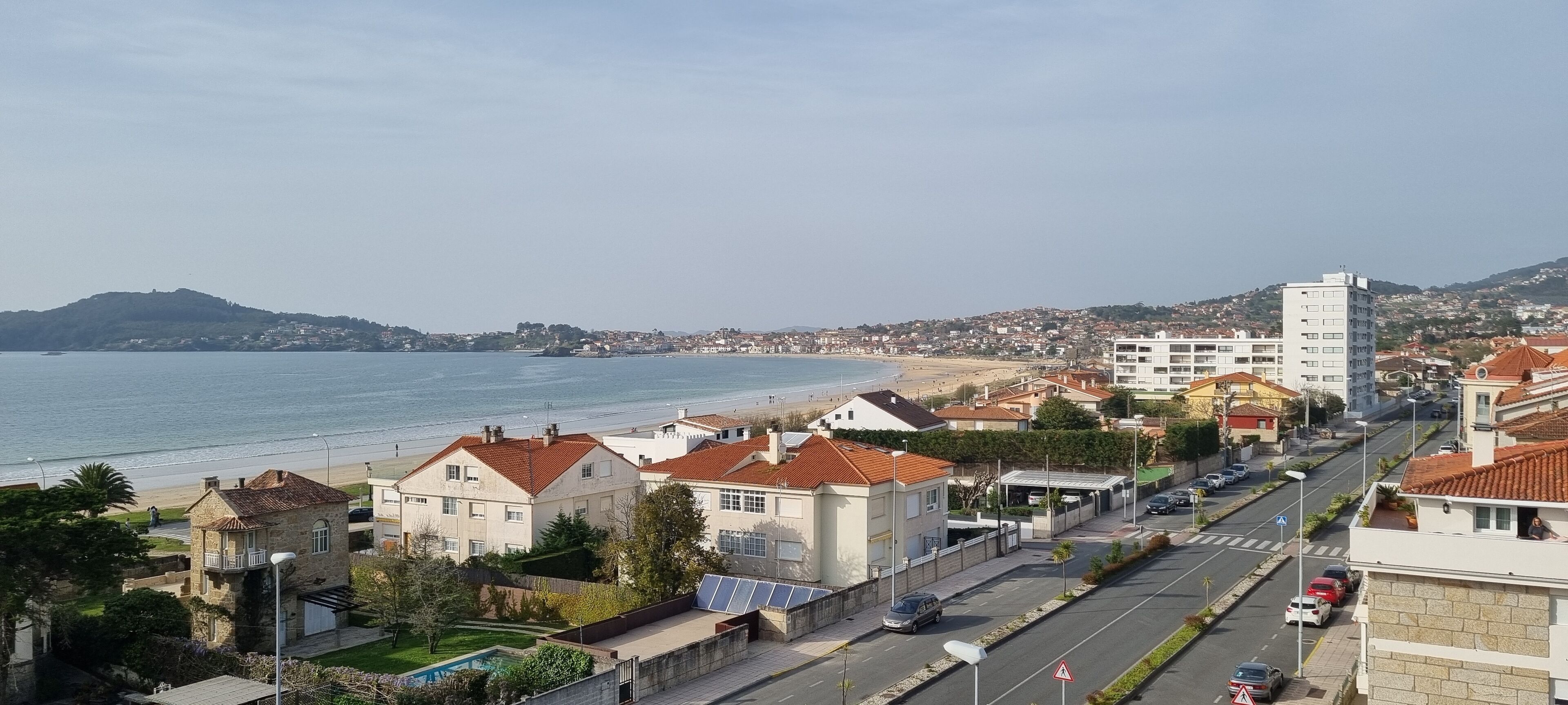 Eine Küstenstadt mit Strand, Wohnhäusern und einer Straße, die zum Meer führt.