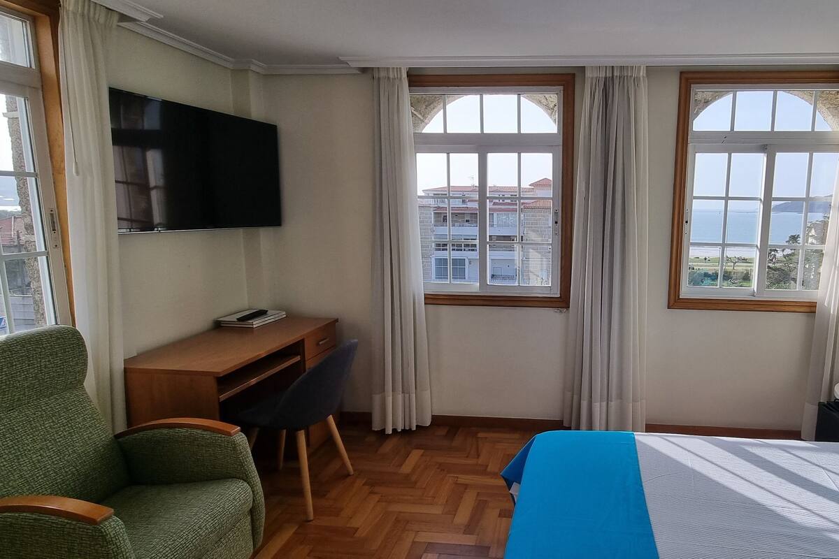 A hotel room with a bed, a desk, a chair, and a TV.