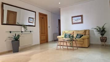Una sala de estar con un sofá, una mesa de centro y dos plantas en macetas.