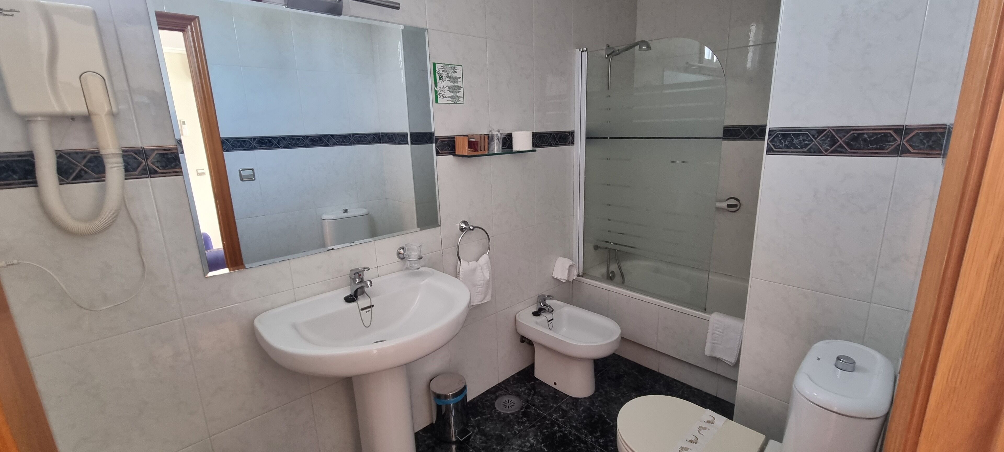 Une salle de bain équipée d’un lavabo, d’un bidet, de toilettes et d’une douche à parois en verre.