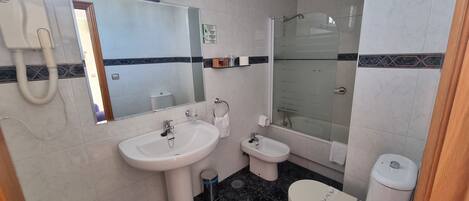 A bathroom with a sink, bidet, toilet, and a glass-enclosed shower.
