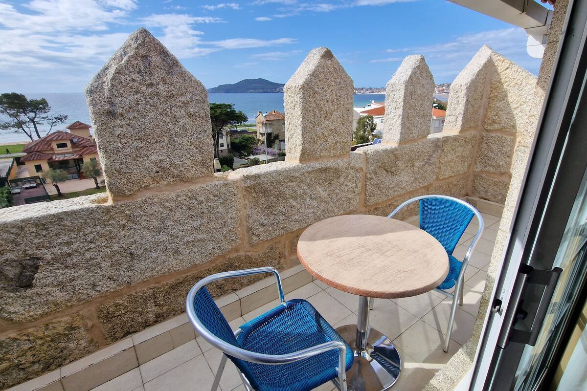 A balcony with stone walls, two wicker chairs, and a small round table.