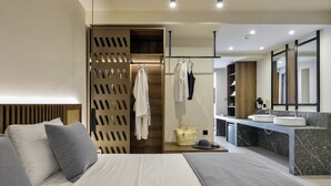 Een moderne hotelkamer met een groot bed, een badkamer met een marmeren wastafel en een houten garderobe.