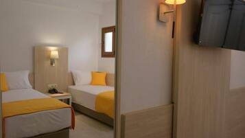 Habitación de hotel con dos camas, televisión, mesita de noche y lámpara.