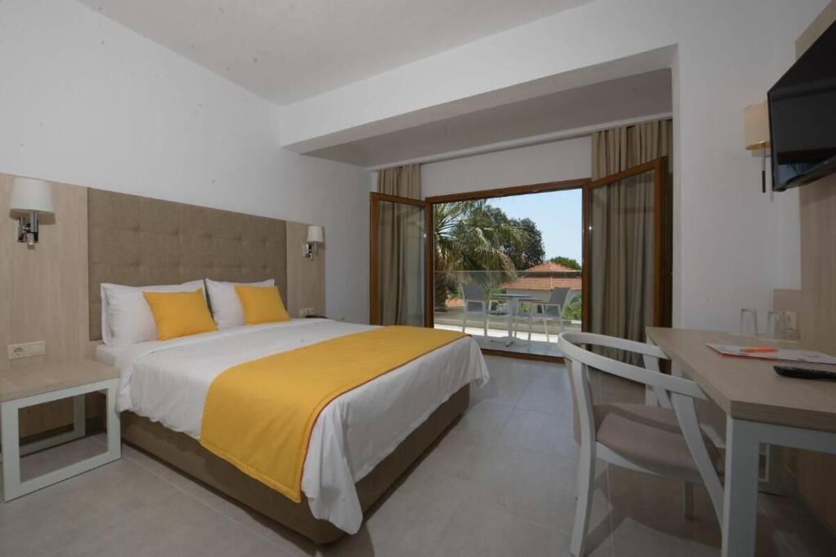 Een hotelkamer met een bed, nachtkastjes, een bureau en een televisie.
