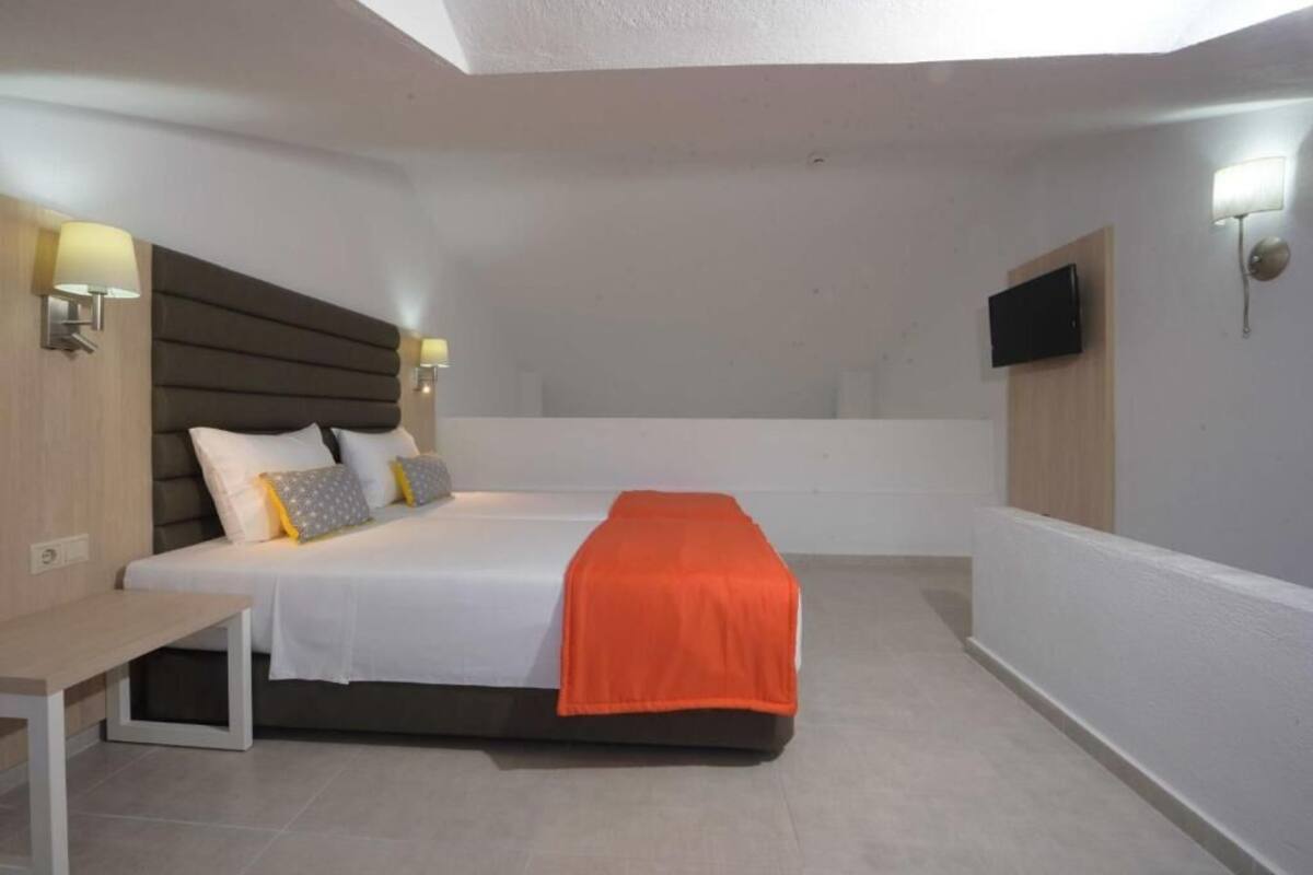 Een slaapkamer met een bed, nachtkastjes, een televisie en een raam.