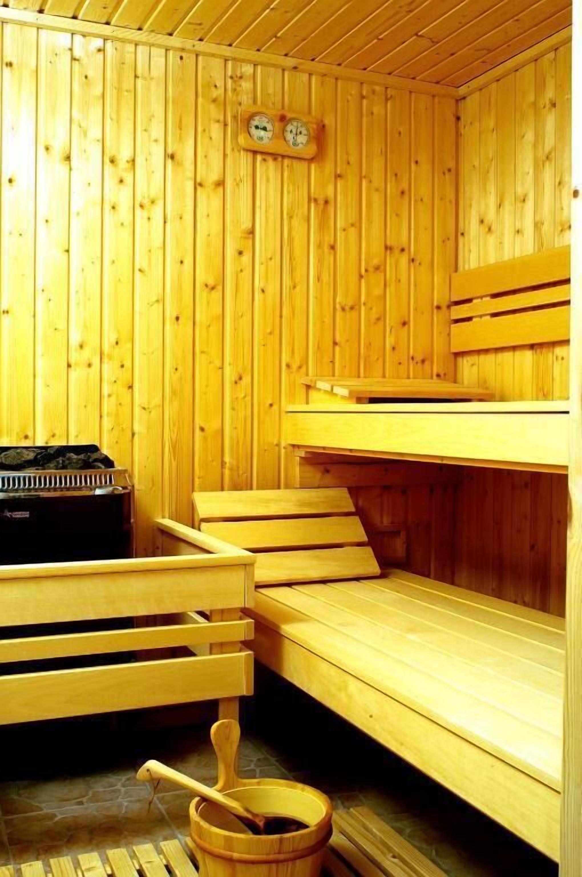 Un sauna avec des bancs en bois et un seau en bois accompagné d’une louche.