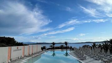 Una piscina techada, una piscina al aire libre, sombrillas