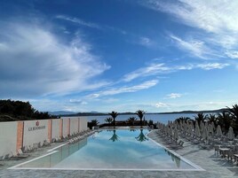 Una piscina techada, una piscina al aire libre, sombrillas
