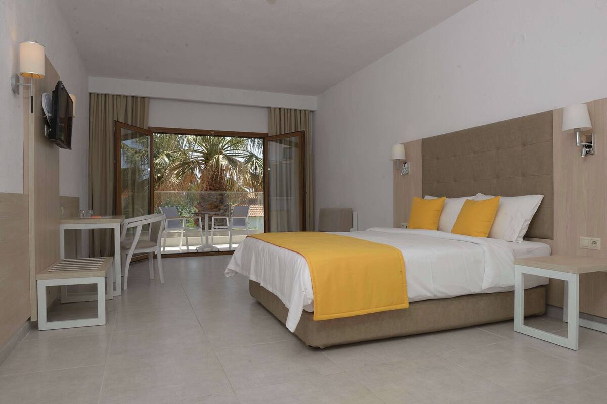 Een hotelkamer met een bed, nachtkastjes, een bureau en een stoel.