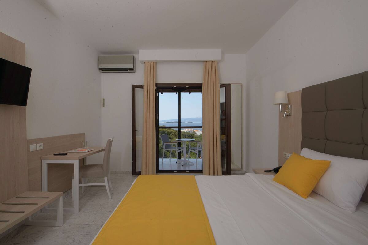 Hotelkamer met een bed, bureau, stoel, televisie en balkon met uitzicht.