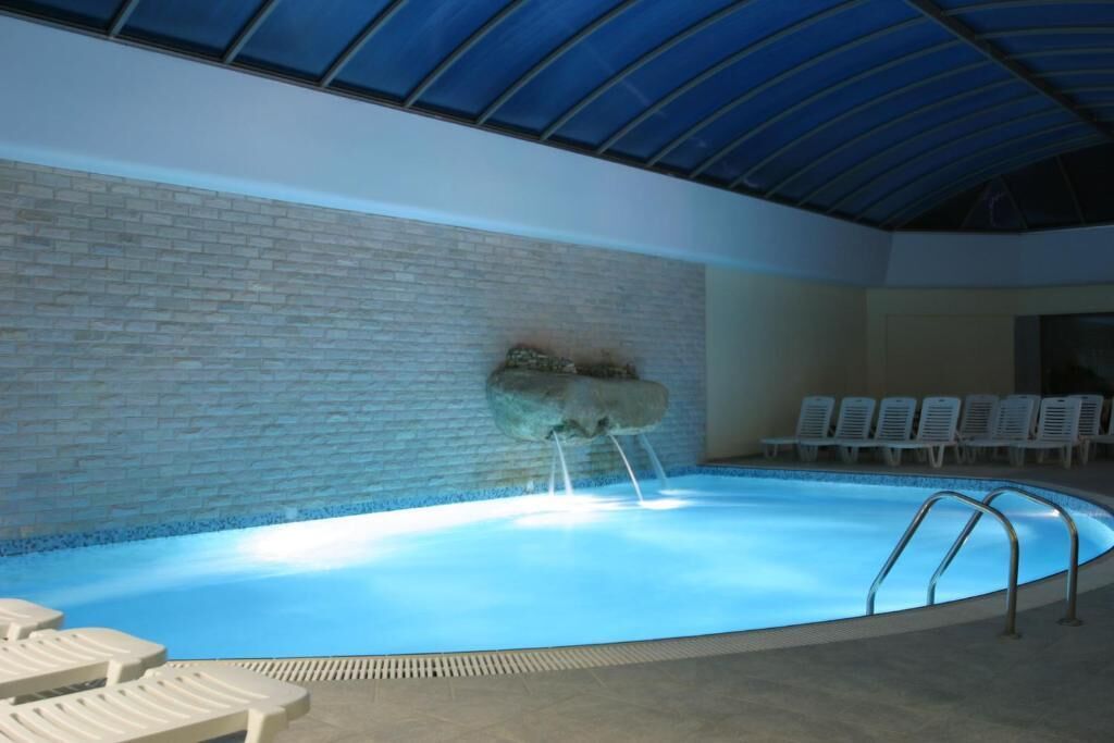 An indoor swimming pool with a brick wall, a rock feature, and lounge chairs.