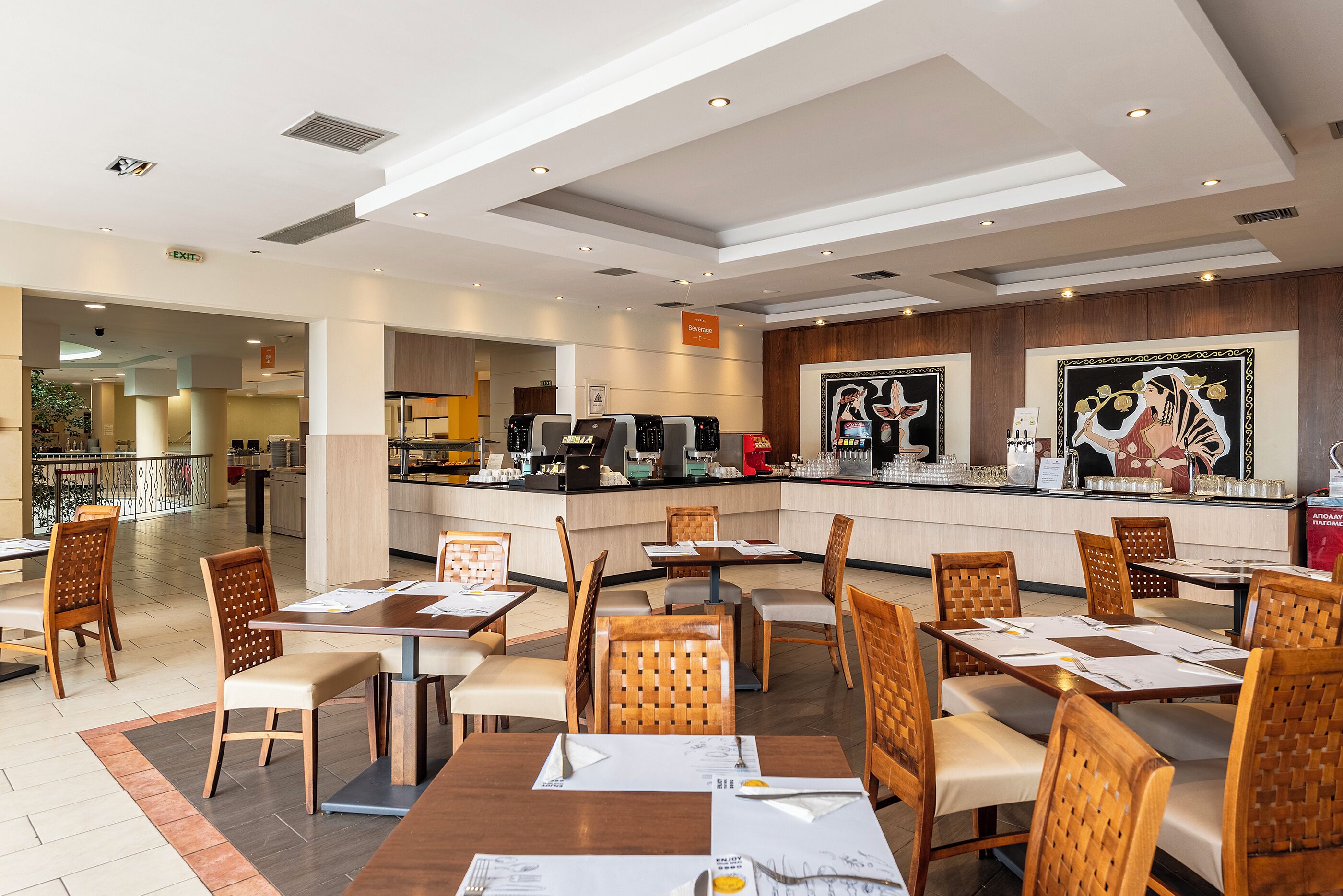 Ein modernes Restaurant mit Holztischen und -stühlen, einer Theke mit Getränkeausgabe und Blick ins Freie.