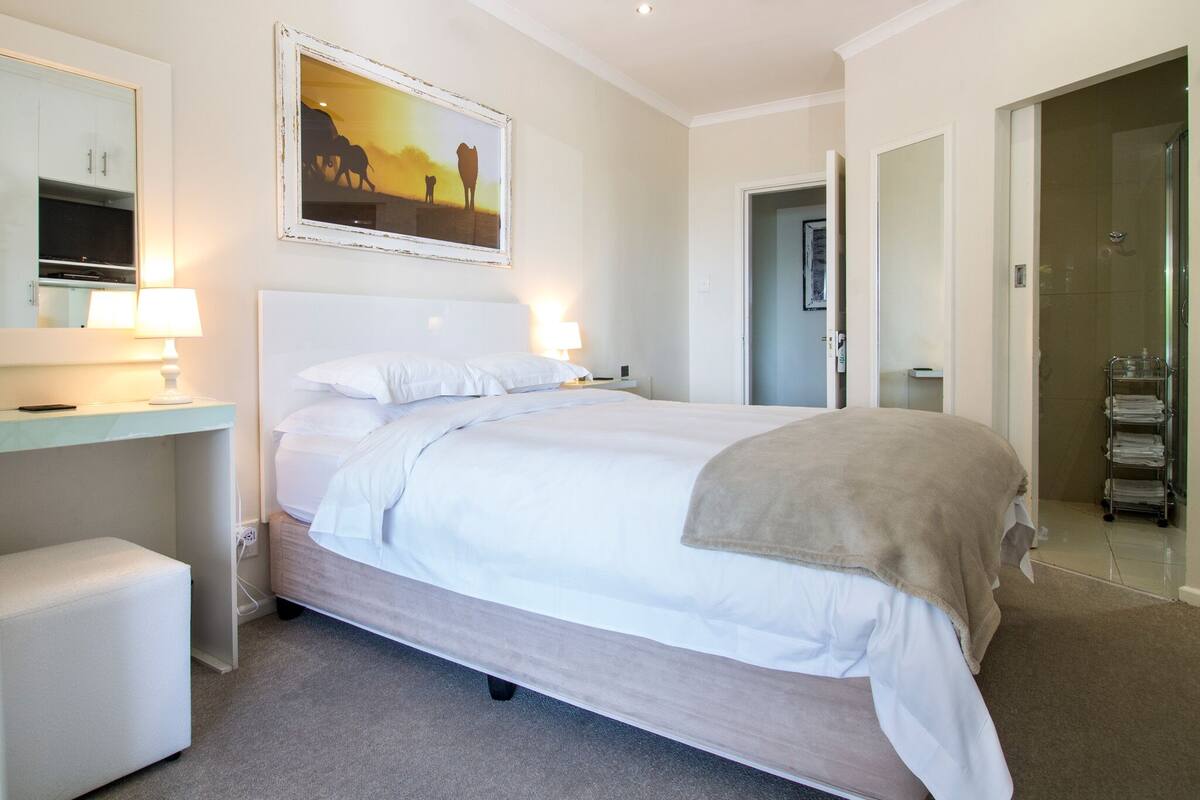 Ein Hotelzimmer mit Bett, Nachttisch, Lampe und einem Bild an der Wand.