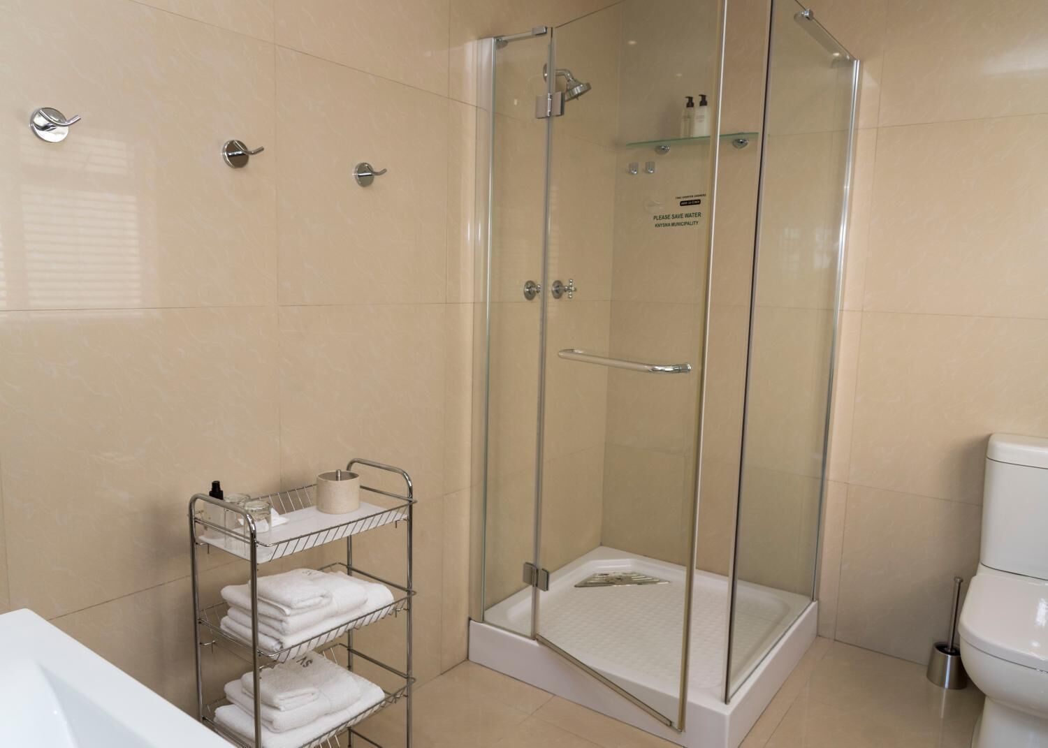 Ein modernes Badezimmer mit einer Duschkabine, einer weißen Toilette und einem Handtuchhalter mit ordentlich gefalteten Handtüchern.