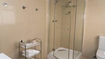 Ein modernes Badezimmer mit einer Duschkabine, einer weißen Toilette und einem Handtuchhalter mit ordentlich gefalteten Handtüchern.