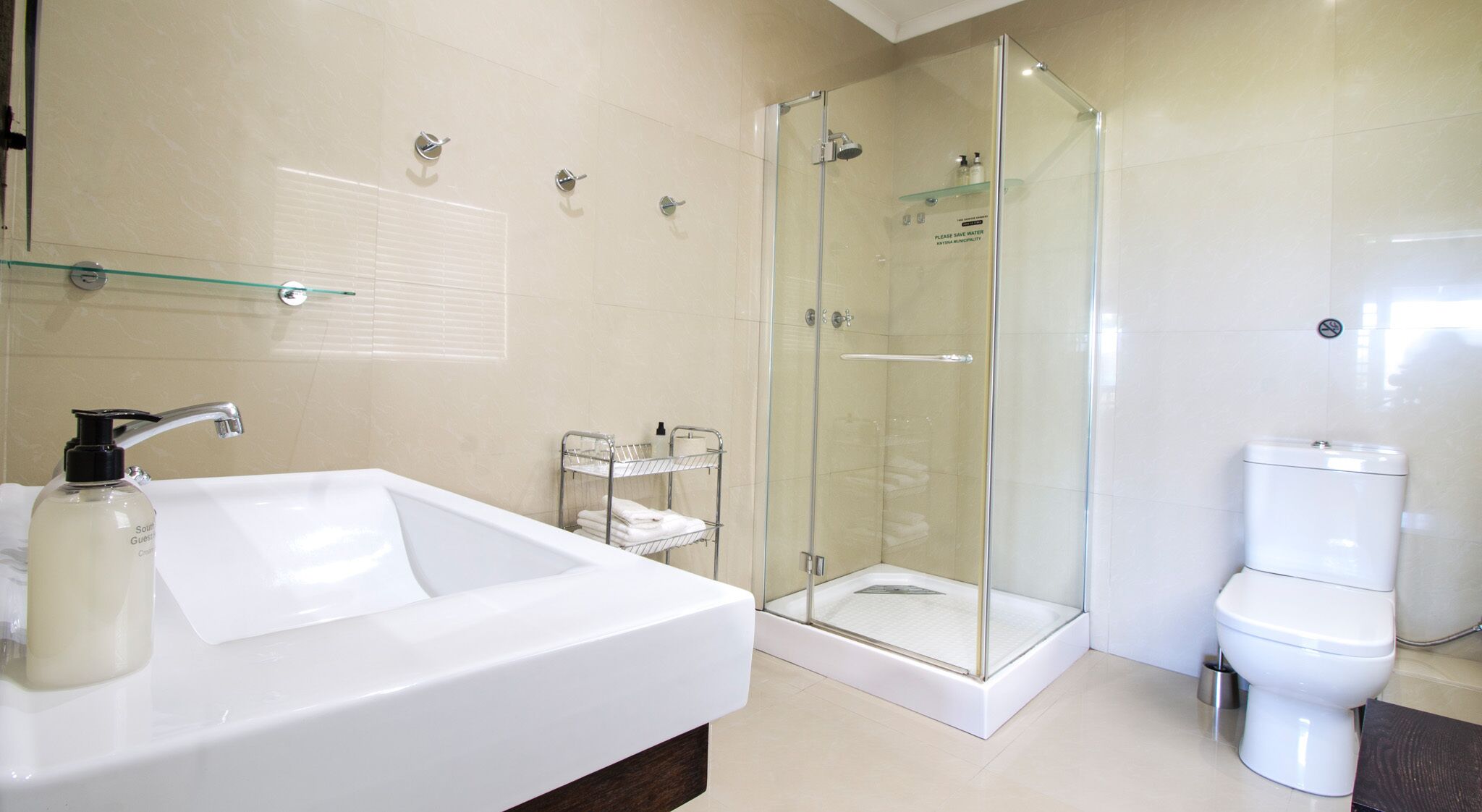 Un baño moderno con un lavamanos grande de color blanco, una cabina de ducha de cristal y un inodoro.