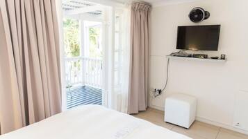 Hotelkamer met een bed, een aan de muur bevestigde televisie, een kleine verwarming en uitzicht op het balkon.