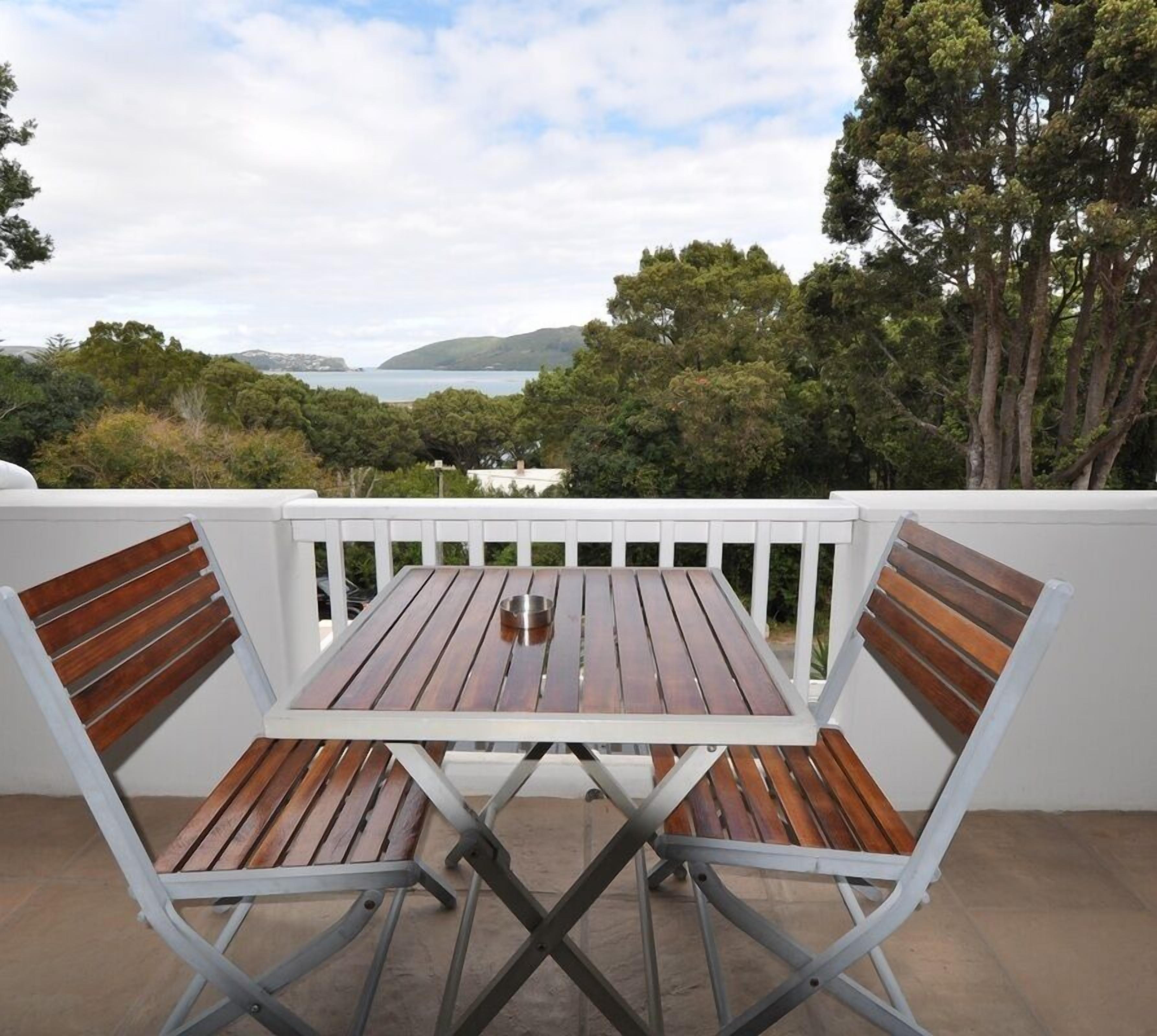 A patio table with a view of the sea and hills.