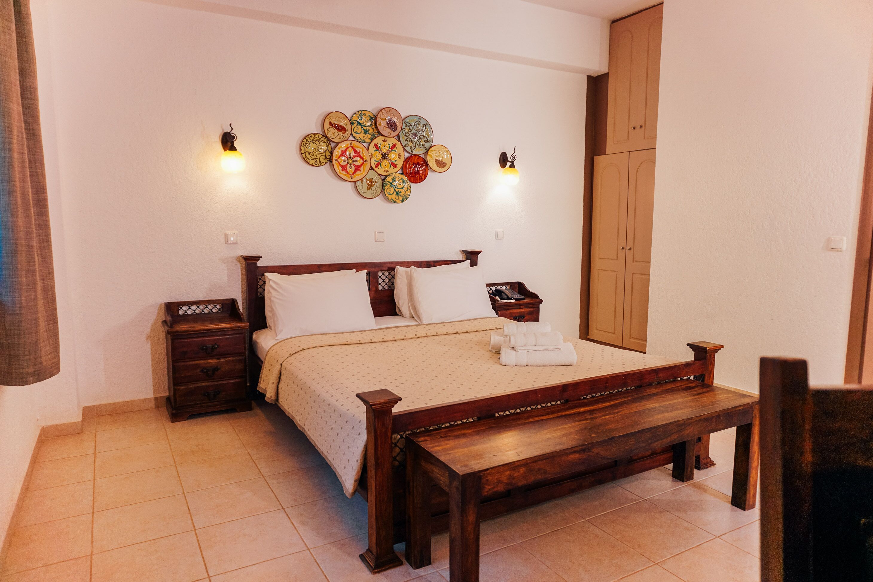 Un dormitorio con una cama de madera, una mesita de noche, una lámpara de pared y un armario.