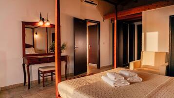 Une chambre d’hôtel comprenant un lit, un bureau, une chaise, un miroir et une porte donnant sur une autre pièce.