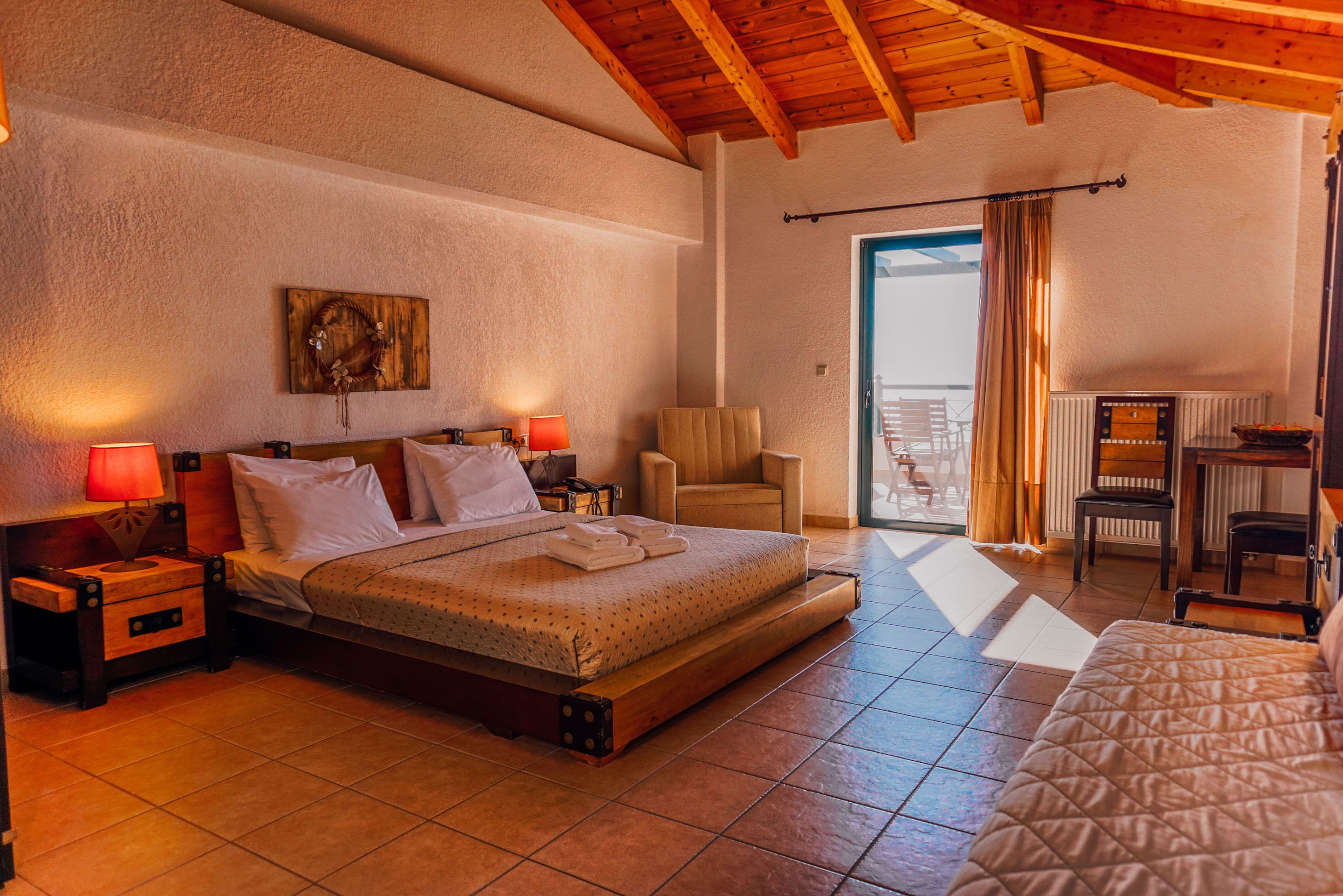 A bedroom with a bed, bedside tables, a chair, and a view of the outside.