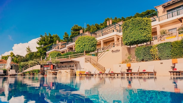 Un hotel con piscina, zona de estar al aire libre y una escalera que lleva a los pisos superiores.
