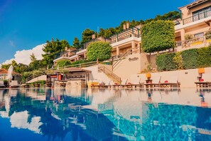 Un hotel con piscina, zona de estar al aire libre y una escalera que lleva a los pisos superiores.
