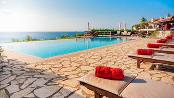 A poolside area with lounge chairs and a view of the ocean.