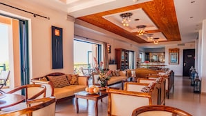 Amplia sala de estar con muebles de madera, una mesa de centro con frutas y vistas al exterior.