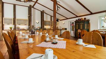 Un grande tavolo da pranzo in legno apparecchiato per un pasto, con sedie, un lampadario e un mobile contenente oggetti decorativi.